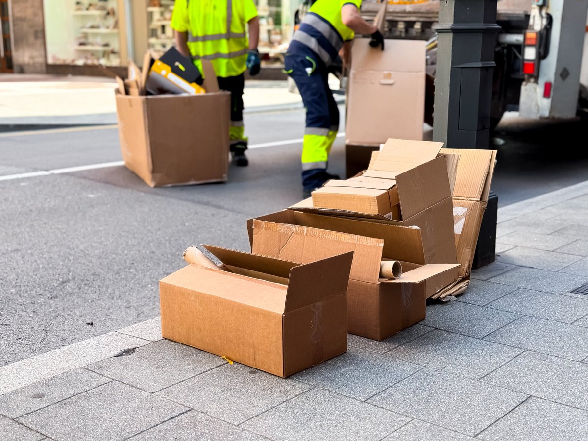 Workers disposing of cardboard boxes on a city sidewalk